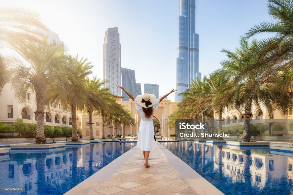 A happy tourist woman in a white summer dress walks through the streets of Dubai, UAE, during her holiday time