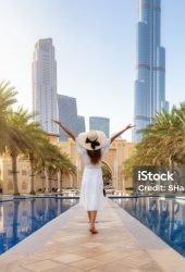 A happy tourist woman in a white summer dress walks through the streets of Dubai, UAE, during her holiday time